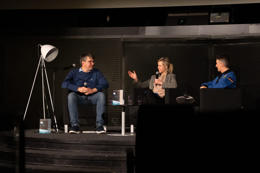 Moderation Kristin Linde, Lesung mit ESA-Astronaut Matthias Maurer und SPIEGEL-Wissenschaftsautor Christoph Seidler, März 2025, Zeiss-Großplanetarium Berlin, © Mark Reichert